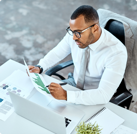 Photo d’un homme assis à son bureau et tenant une feuille avec un stylo