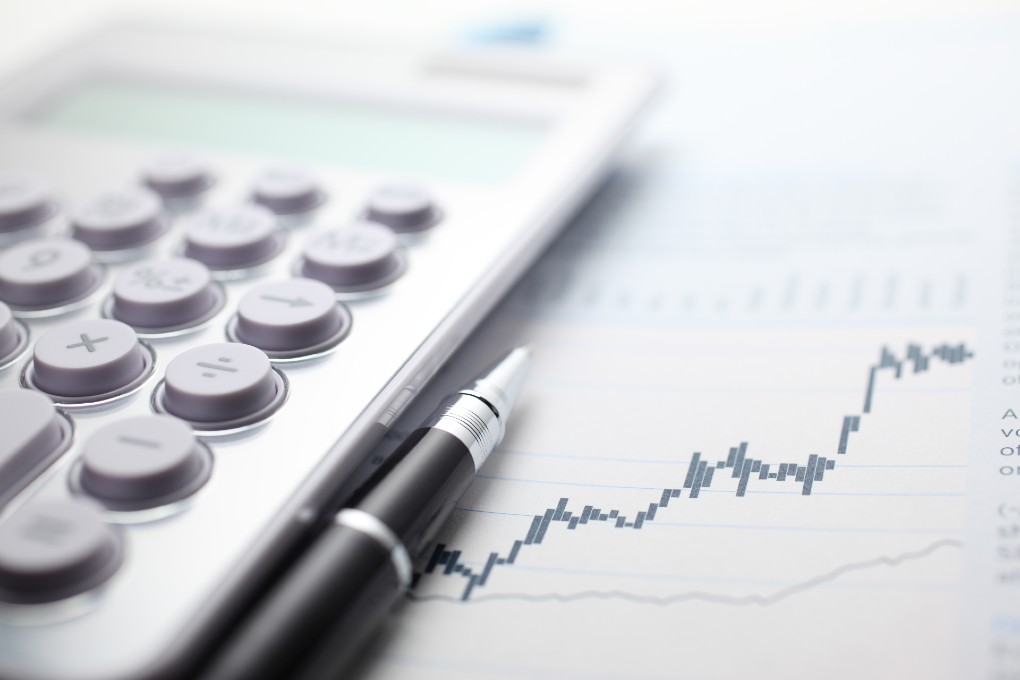 Une calculatrice et un stylo déposés sur un graphique. Une calculatrice et un stylo déposés sur un graphique.